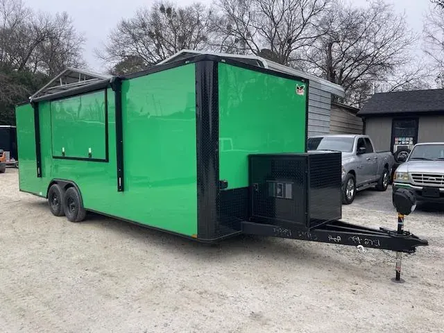 Bright green concession trailer with a service window, black trim and a tongue box, on a gravel trailer lot