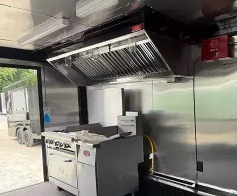 Stainless steel food trailer kitchen with an exhaust hood, fire suppression system and a gas range with griddle and oven