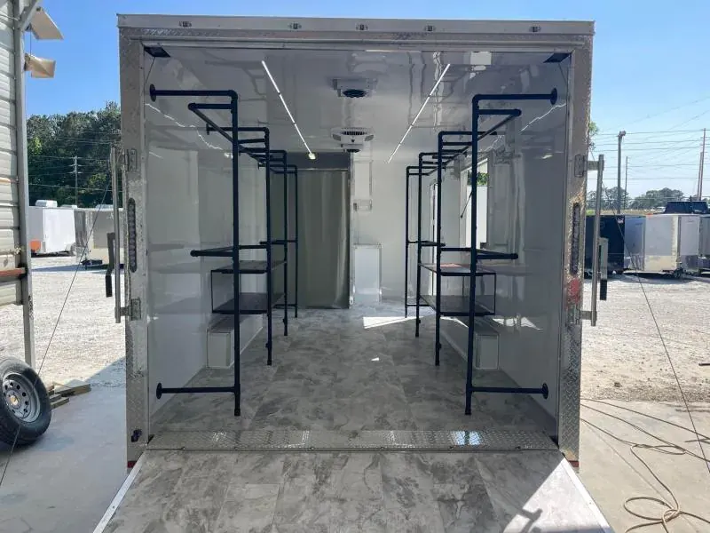 Mobile boutique trailer with rear doors open, showing black pipe clothing racks, a marble-look floor and a fitting-room curtain